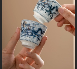 Close-up of blue and white dragon pattern teacup with gold rim and wave base detail