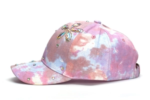 Dettaglio cappellino tie-dye con strass floreali colorati e finiture glitterate