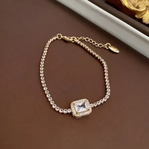 Gold tennis bracelet with rectangular zircon centerpiece on a luxury leather background