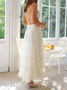 Detail of white backless halter maxi dress featuring thin straps and tiered cake skirt