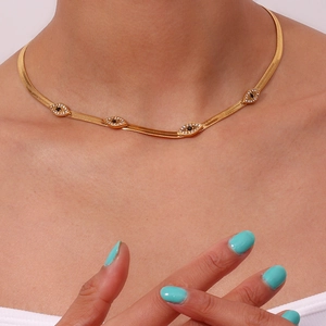 Close-up of gold snake chain necklace with four crystal evil eye charms on a model