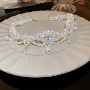 Close-up of white pearl flower necklace with crystals on a decorative white plate