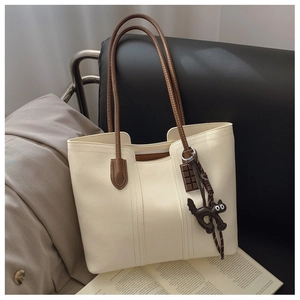 Detail view of cream tote bag featuring dark chocolate and cartoon cat charms
