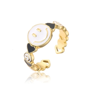 Detailed macro view of gold plated open ring featuring white smiley face and heart enamel