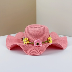 Close-up of pink straw hat with wave brim and decorative yellow floral headband