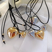 Macro shot of 3D heart-shaped pendants in gold and silver on white silk fabric