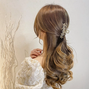 Elegant gold hair claw clip featuring five white crystal flowers on a half-up hairstyle