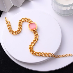 Détail d'un bracelet gourmette doré avec une pierre précieuse rose carrée sur un socle