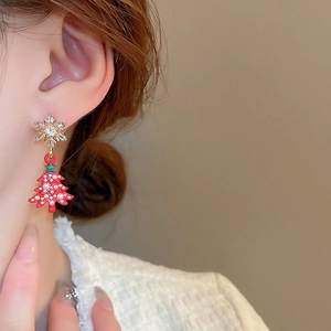 Close-up of red Christmas tree earring with gold snowflake stud and pearls on model