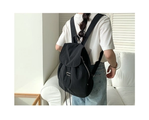 Vista laterale di una donna con zaino in nylon nero su uno sfondo bianco minimalista