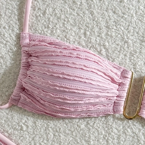 Close-up of ruched pink bikini fabric with stylish gold U-shaped metal buckle detail