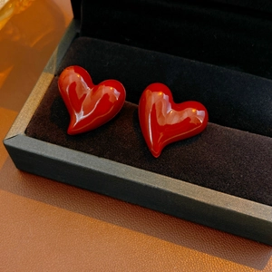 Macro shot of red enamel heart-shaped earrings resting in a black velvet jewelry gift box