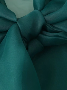 Nahaufnahme des eleganten smaragdgrünen Organza-Stoffs, zu einer Schleife gebunden