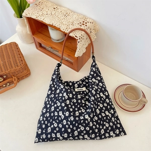 Détail du sac cabas en toile florale avec anses en cuir marron et étiquette de marque