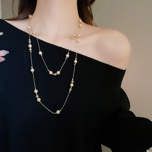 Détail d'un collier long à double rangée avec perles et cristaux sur un mannequin