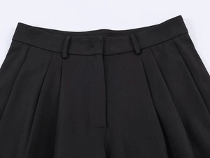Detailed close-up of the black dress trousers waistband featuring refined pleated details