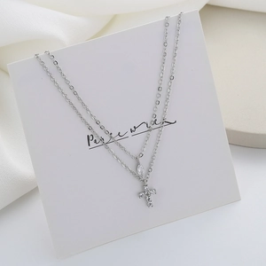 Double-layered silver necklace with marquise zircon and crystal cross pendant on white base