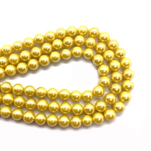 Close-up of polished golden glass pearl beads for DIY jewelry and necklace crafting
