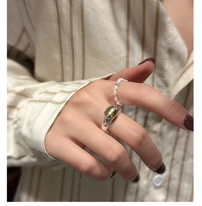 Detail of stacked S925 silver rings featuring gold oval inlay and delicate pearl beads