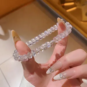 Bracelet en perles de cristal irisé avec pendentif lotus présenté de près à la main