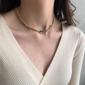 Detail of 18K gold titanium necklace with emerald gemstone on model neck