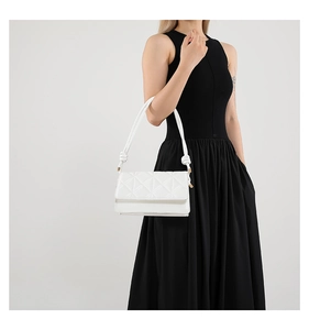 Detail of white quilted crossbody bag featuring unique knot decor on the shoulder strap