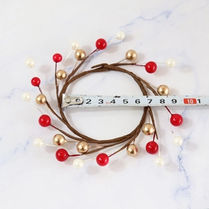 Christmas candle ring with red gold and cream berries on white marble surface