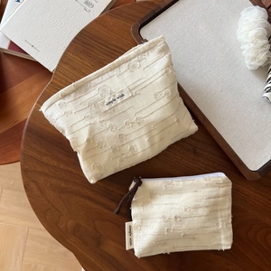 Detail of two-piece cream textured fabric storage bags with simple wish woven labels