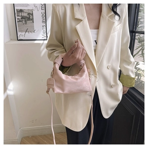 Detail of pink pleated mini dumpling bag featuring suede texture and gold chain strap