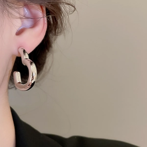 Gros plan sur les boucles d'oreilles minimalistes argentées en forme de C portées par un mannequin