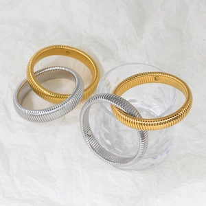 Close-up of gold and silver tubogas snake chain bracelets on textured glass and paper