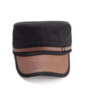 Close-up of black canvas military cap with brown leather brim and metal emblem