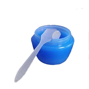 Blue translucent cosmetic jar with two white spatulas for facial mask mixing and skincare