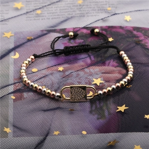 Close-up of tricolor beads and gold heart padlock charm on a black braided bracelet