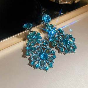Close-up of elegant blue floral earrings with sparkling crystals and starburst light effect