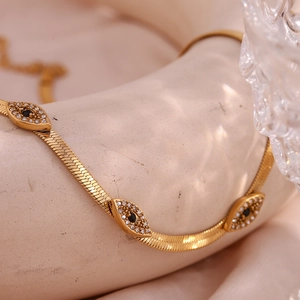 Close-up of 18K gold plated snake chain necklace with three evil eye crystal charms