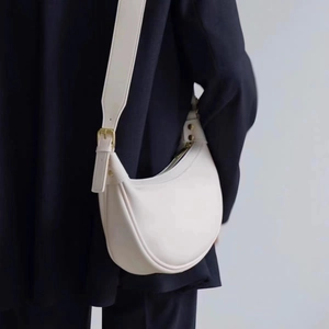 Minimalist beige crescent saddle bag with leather texture and golden metal buckle