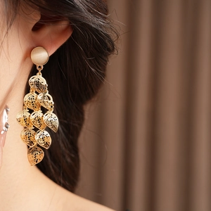 Detail of gold leaf tassel earring with opal stone shown on model for elegant drape