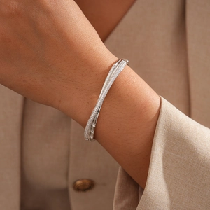 Detailed view of a silver crisscross bangle with micro-paved cubic zirconia on model