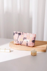 Detailed close-up of floral embroidery and brand label on a pink fabric makeup bag
