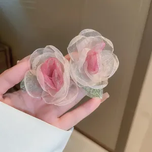 Macro detail of delicate pink gradient organza flower earrings with green embroidered leaves