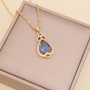 Close-up of a gradient teal teardrop crystal necklace in a luxury jewelry box