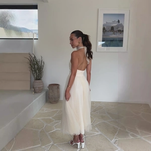 Detail of elegant beige mesh halter dress featuring a low back and layered tulle skirt