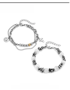 Detail of layered titanium steel chain bracelet with cross charm and white beaded jewelry