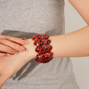 Détail du bracelet élastique à maillons ovales imprimé léopard rouge et noir au poignet