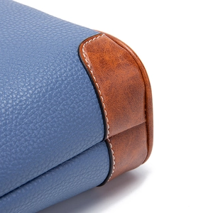 Detail of blue pebble grain leather bag with brown patch and white contrast stitching