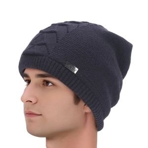 Detail of dark grey knit slouchy beanie with cable pattern and metal logo plate