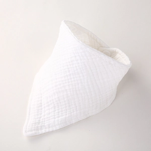 Détail du bavoir en mousseline de coton blanc montrant le tissu texturé et le bouton pression