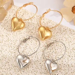 Detail of 3D heart pendants in gold and silver finishes on a minimalist hoop earring set