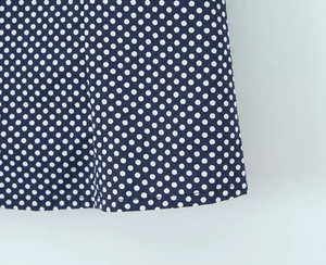 Detail view of navy blue fabric with white polka dots and high-quality hem stitching
